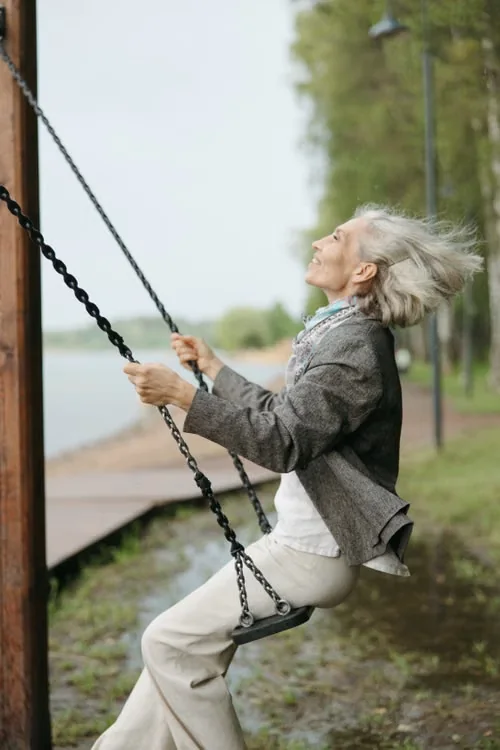 Older woman swinging on a swingset.