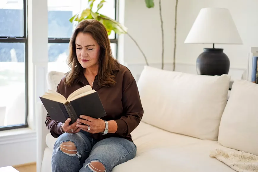 A woman sitting on a couch reading a book